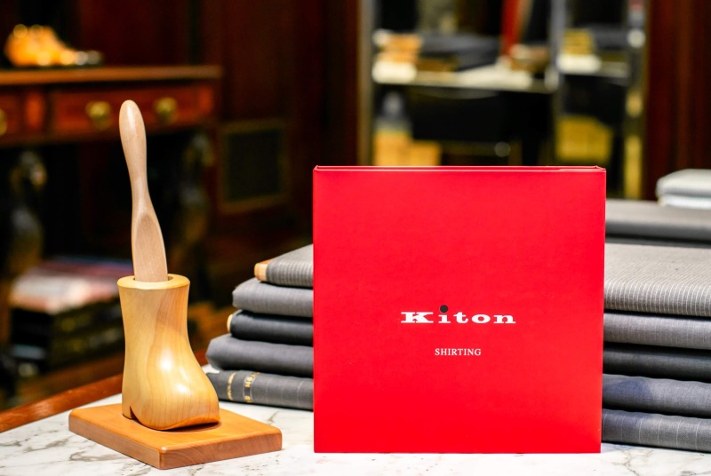 Kitonの赤い冊子の隣に置かれた小さな靴型スタンドと木製靴べら